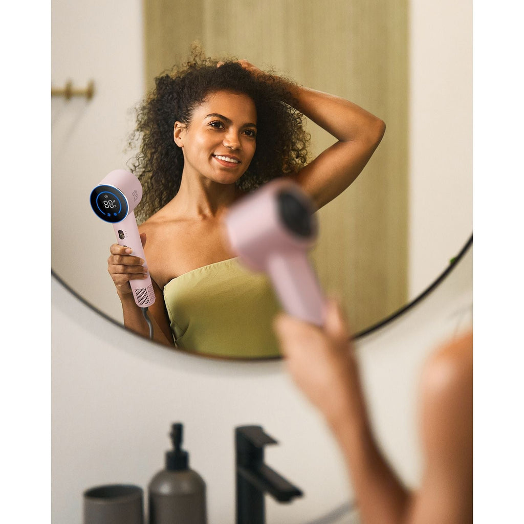 Pink FanttikSolo Aura H10 APEX hair dryer with digital display held by smiling woman