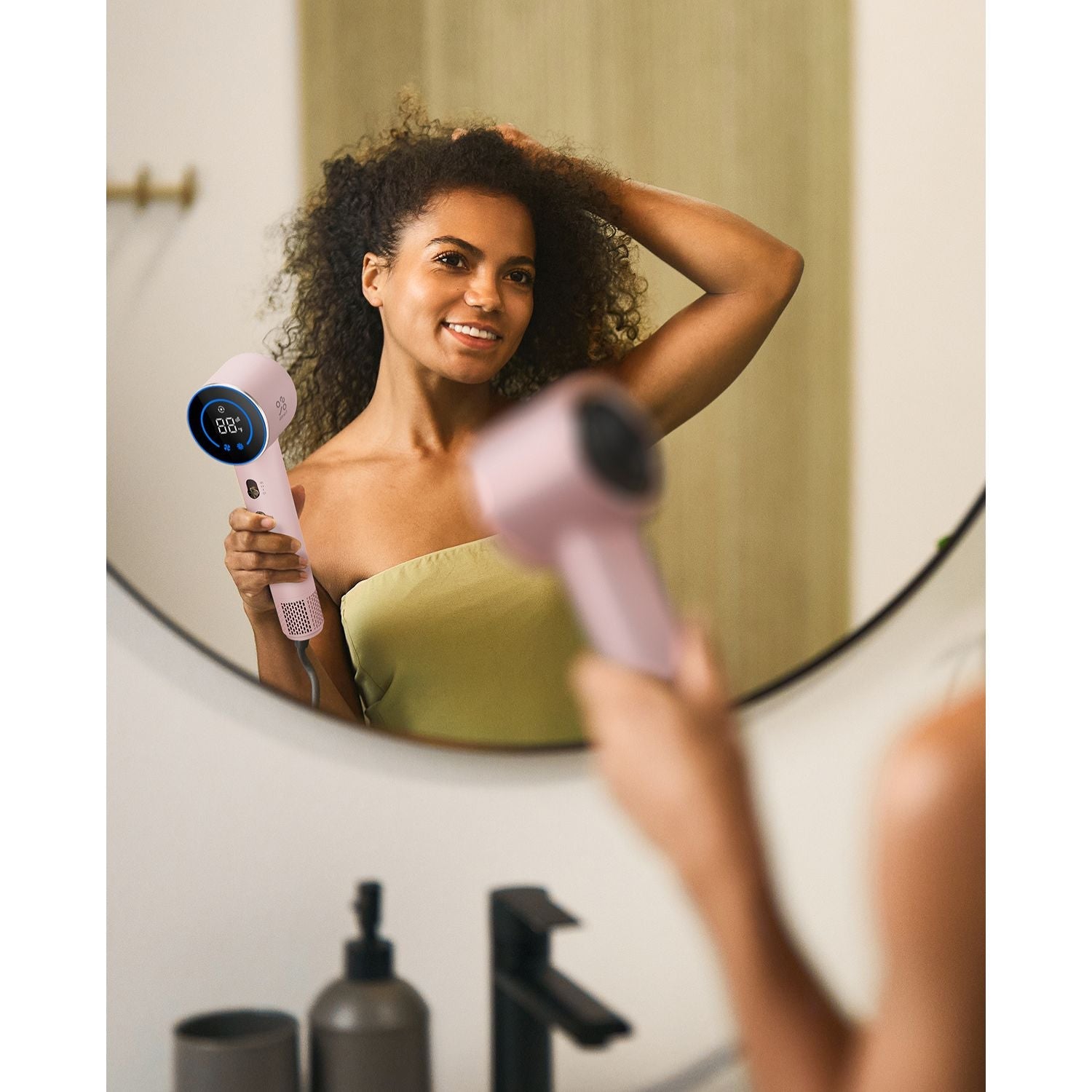 Pink FanttikSolo Aura H10 APEX hair dryer with digital display held by smiling woman