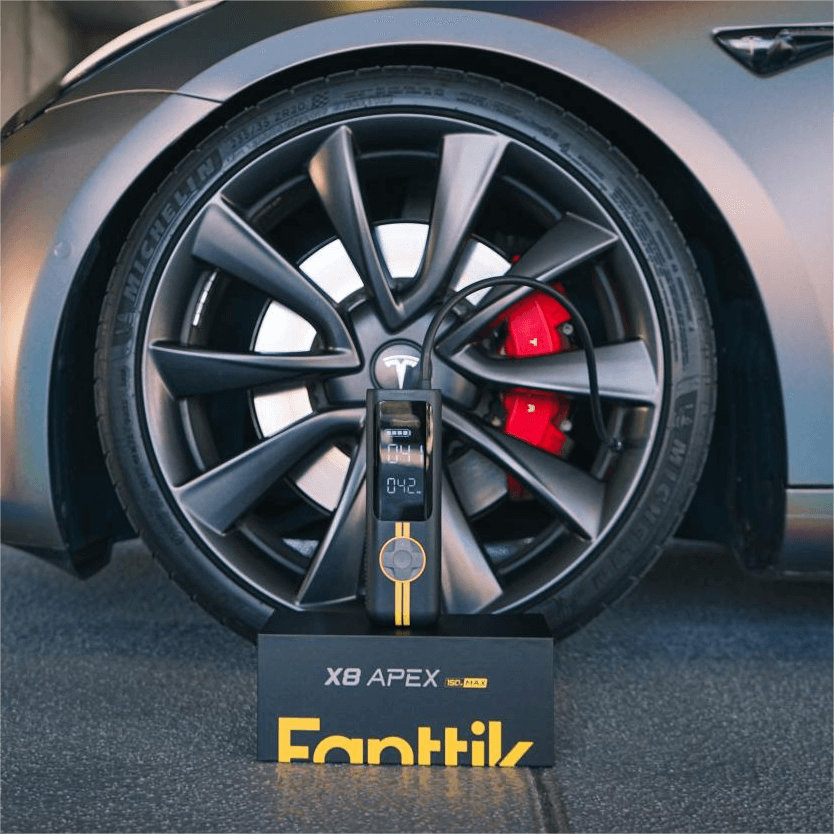 Fanttik X8 APEX EV tire inflator beside Tesla wheel, black and yellow portable pump