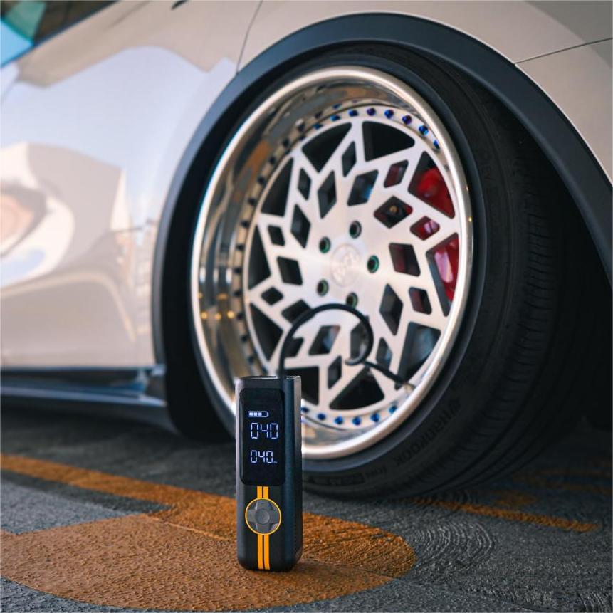 Fanttik X8 APEX EV tire inflator beside a car wheel, portable black air pump with digital display