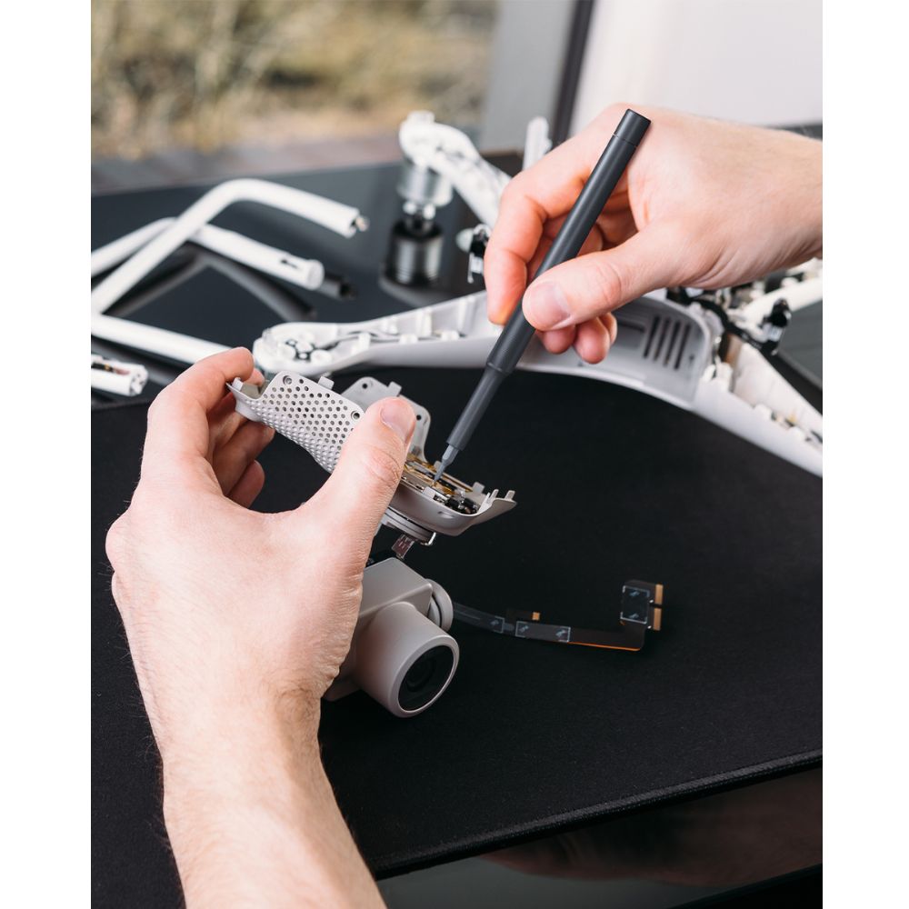 Fanttik X5 MAX precision screwdriver repairing drone electronics on black desk