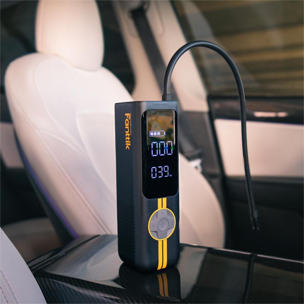 Black Fanttik X8 APEX EV tire inflator with yellow stripes, digital display shows 39 PSI in car. Keywords: Fanttik X8 APEX EV tire inflator.