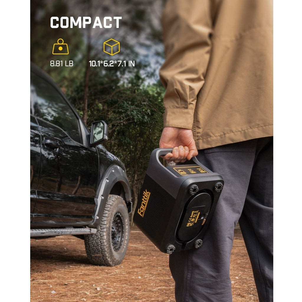 Person holding a black Fanttik X9 Ultra portable tire inflator next to an off-road vehicle.